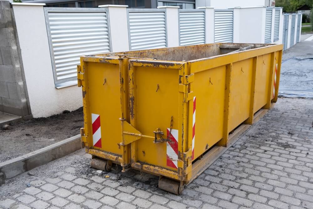 Reduced size of small and narrow yellow metal dumpsters container.